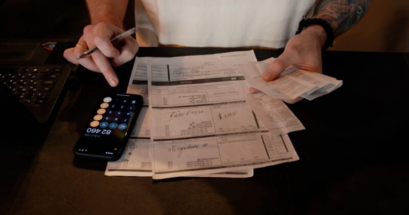 Person calculating expenses with receipts and invoices for small business accounting