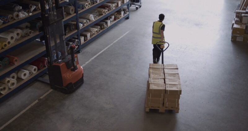Employee transporting packages in a warehouse, highlighting logistics for an e-commerce business in Delaware